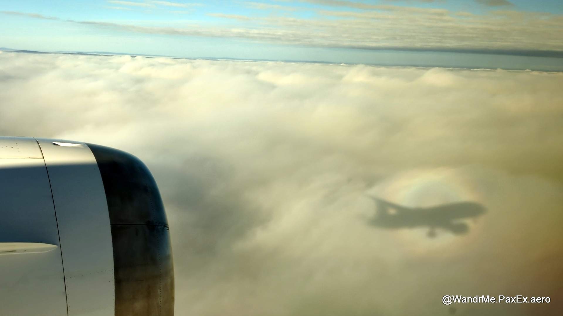 shadow of a plane creating a rainbow on the clouds below