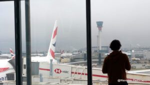guy looking out the window at LHR at an A380 and the control tower.