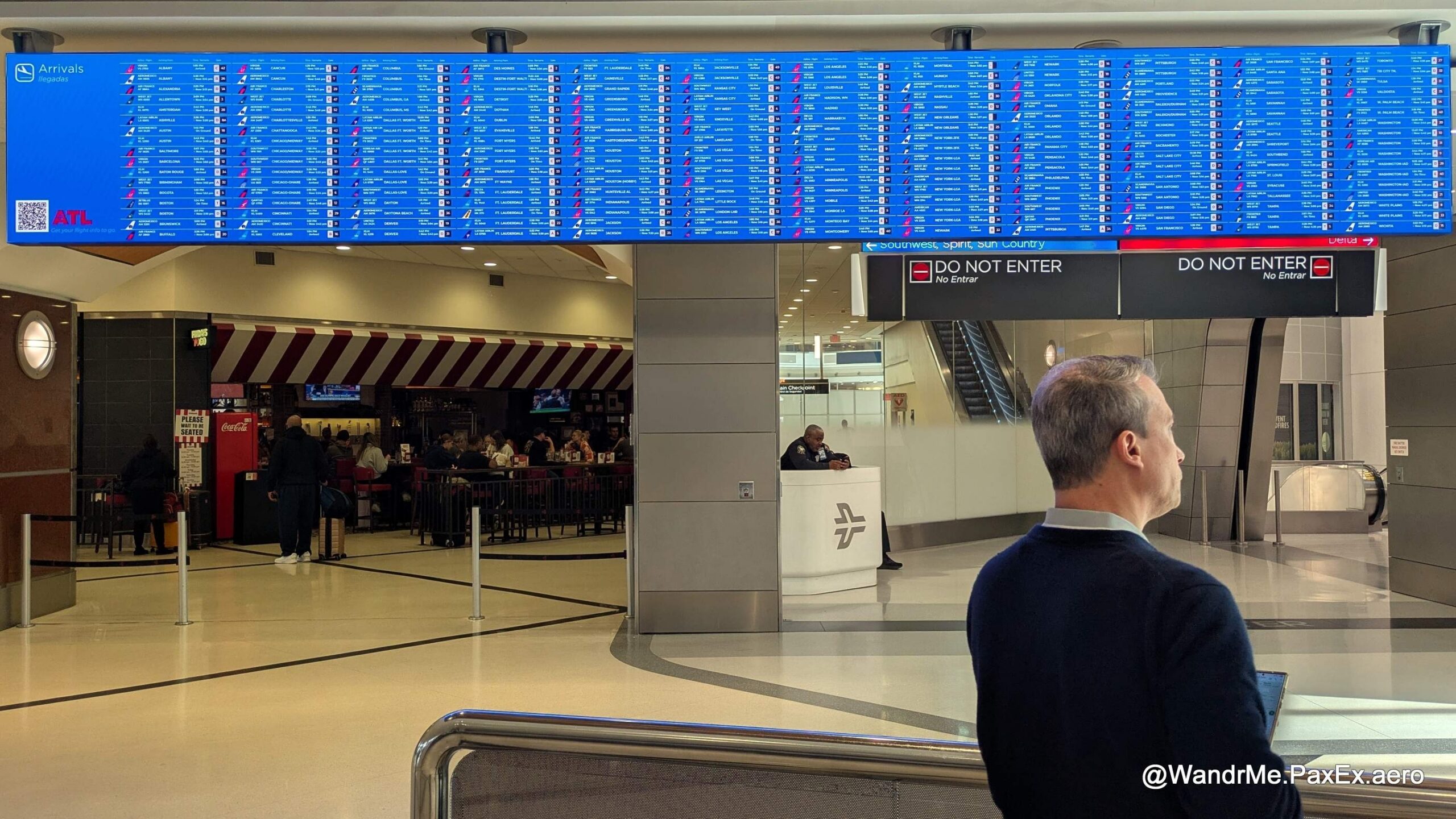 man standing in front of a 12 screens wide flight information display