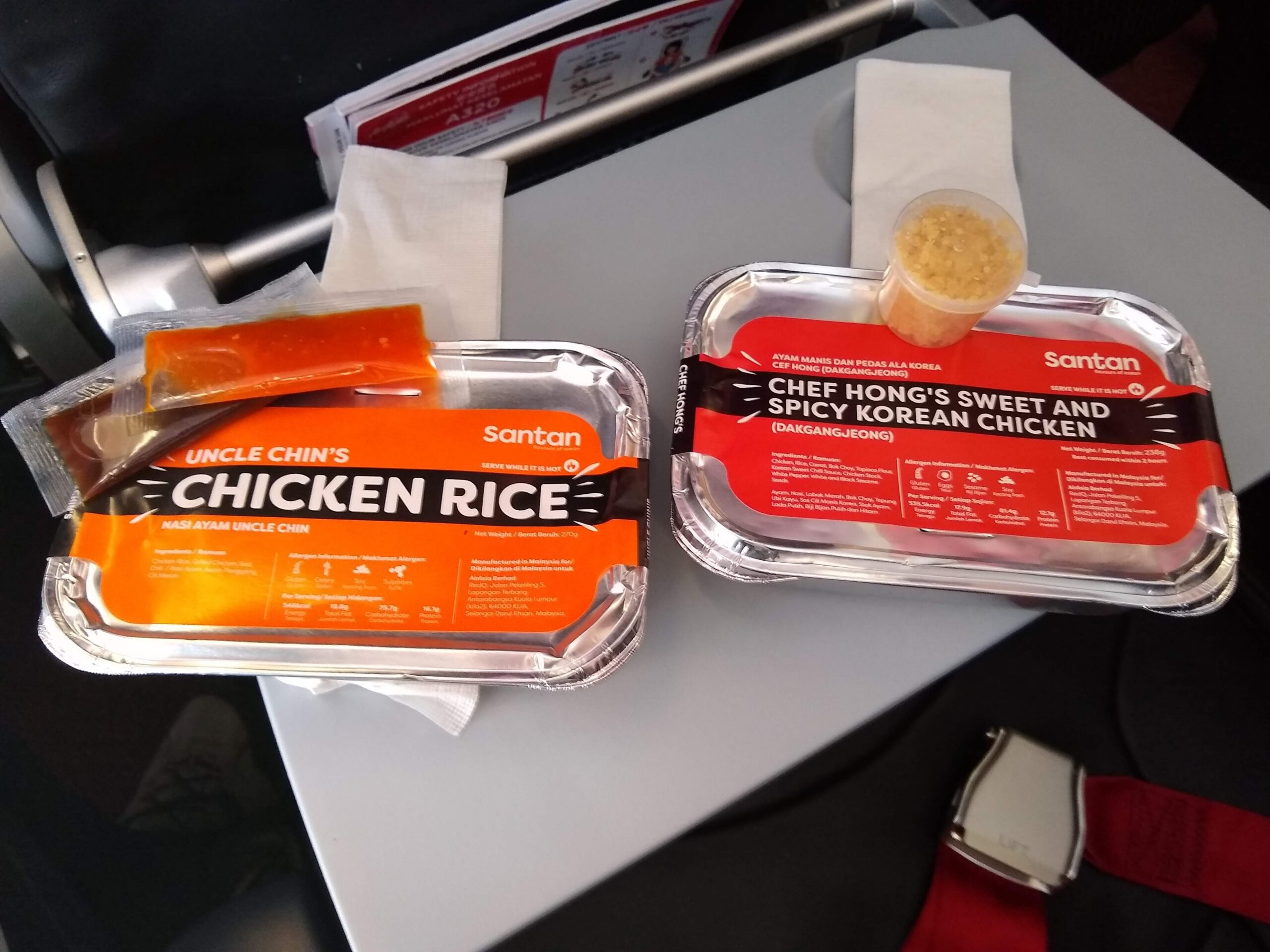 pair of inflight meals packed in foil trays on a tray table