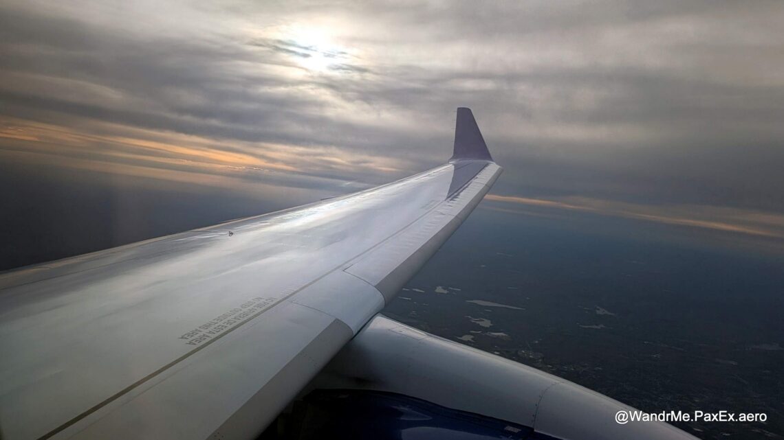 airplane wingtip in flight with a cloudy sunet